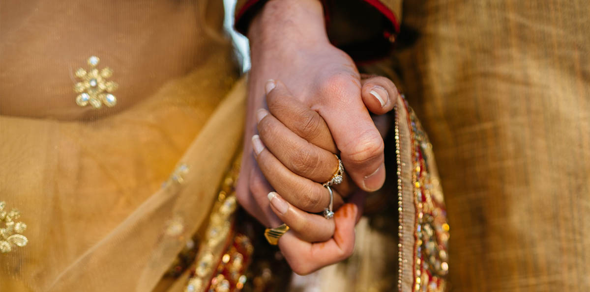 Close up image of bride and groom holding hands