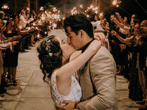 Image of bride and groom kissing at a large wedding party in a lavish hall